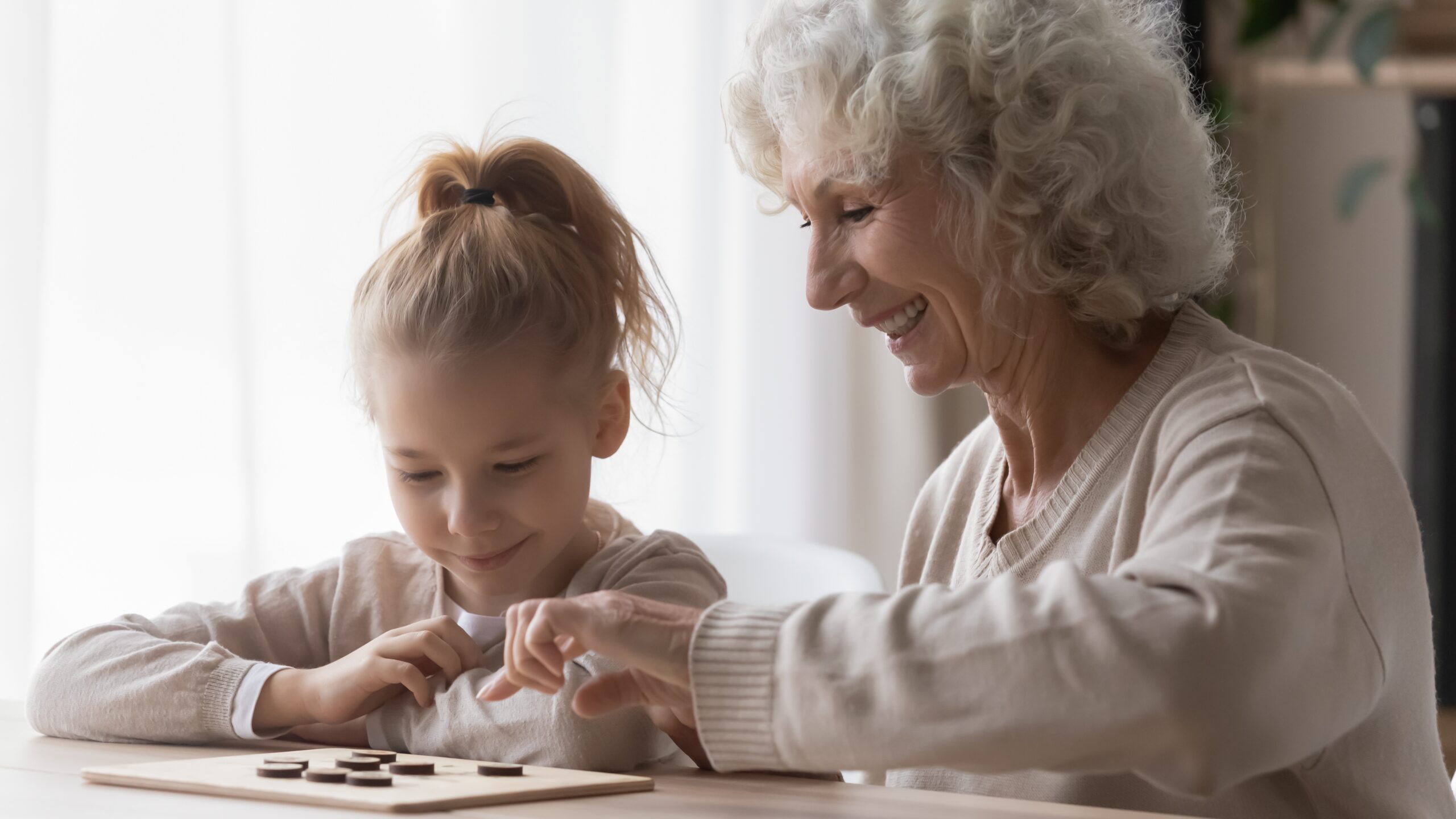 Cheerful,Curious,Adorable,Small,Kid,Girl,Learning,Playing,Checkers,With Young Child Interacting with Elderly Woman