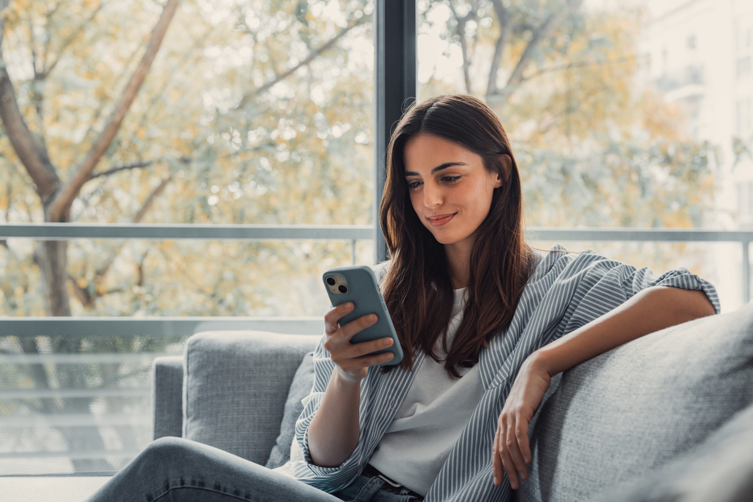 Happy,Pleasant,Millennial,Woman,Relaxing,On,Comfortable,Couch,,Holding,Smartphone Woman On Phone